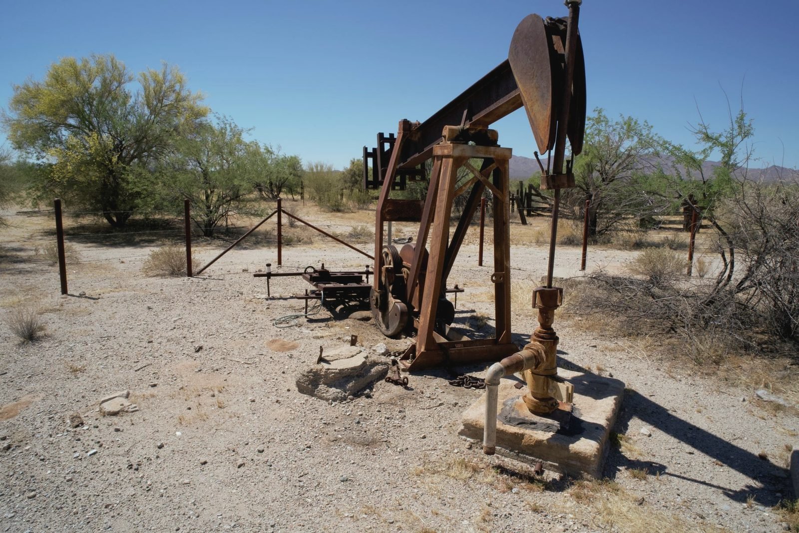 Rusted pumpjack standing in dry desert scrub