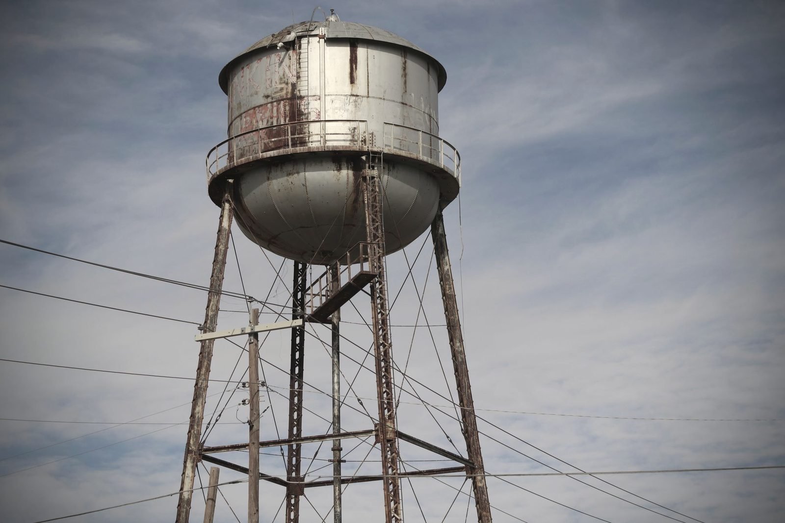 Weathered steel water tower on a lattice frame under a high sky